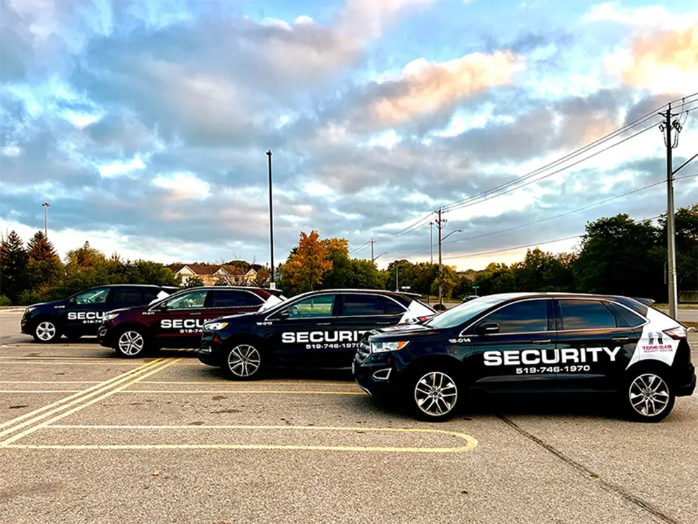 Fleet of Tone-Gar security patrol vehicles in a parking lot, emphasizing the mobile security services offered by the company